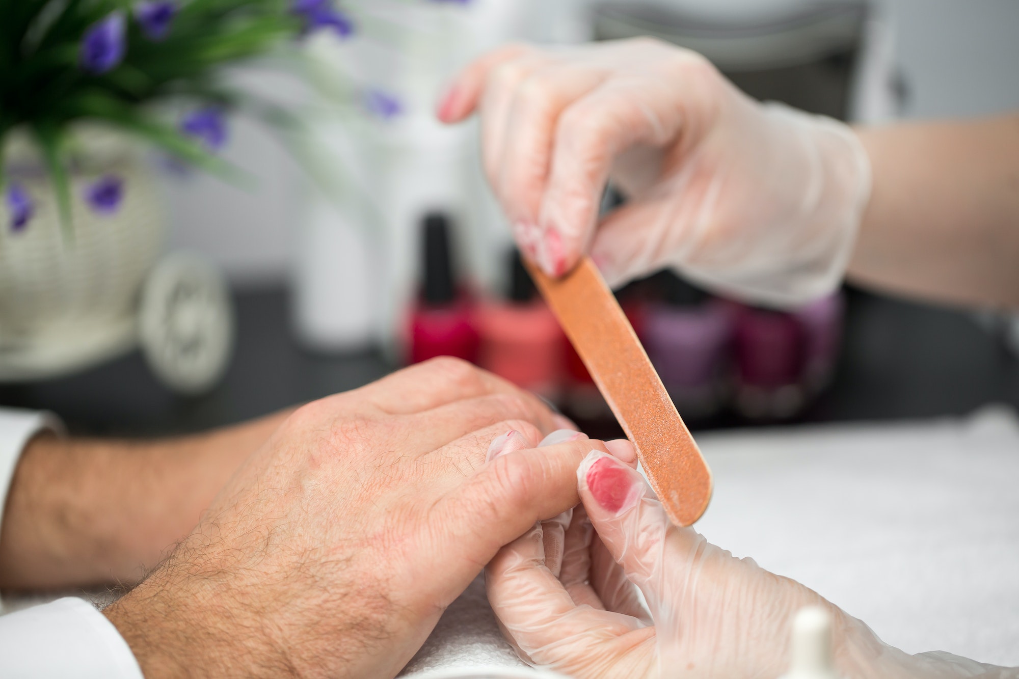 Girl manicurist doing manicure for man in beauty salon